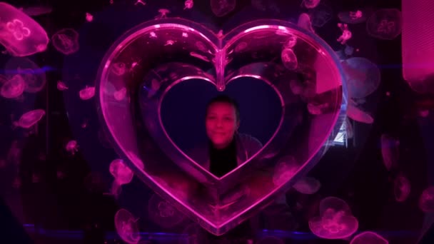 Woman inside abstract heart aquarium made of jellyfish. Pink Moon Jellyfish or Aurelia Aurita or Saucer Jelly. Valentines day concept. — Stock Video