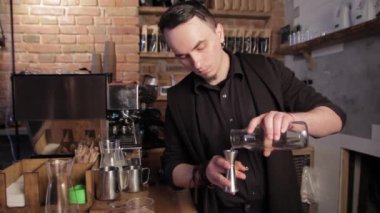 Barista İrlanda kahvesi yapıyor. Viski bardaklarına su dökerek.