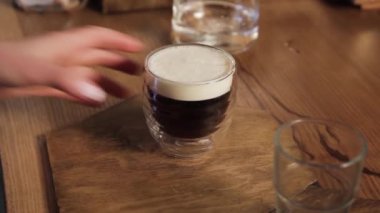 Kadın eli bir kafede bir fincan İrlanda kahvesi içer. Misafirin eli restoranda bir fincan alıyor..