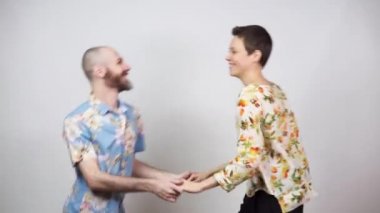 Mutlu çift eğleniyor. Beyaz arka planda Hawaii gömleği giyen swing dansçıları..