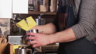 İtalyan kahve makinesi. Profesyonel barista cappuccino yapıyor. Barista metal bardağa çırpılmış süt dolduruyor..