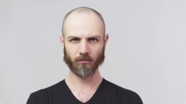 Beyaz arka planda kameraya bakan sert sakallı bir adam. Ciddi derecede tatminsiz bir adam. Duyguların kavramı.