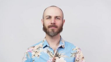 Sakallı sakallı adamın portresi beyaz arka planda izole edilmiş Hawaii gömleği giymiş kameraya bakıyor. Duyguların kavramı.
