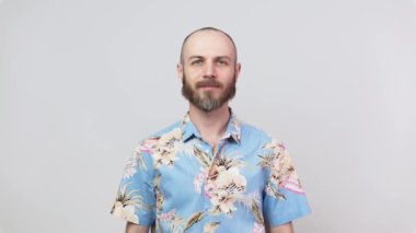 Hawaii gömleği giyen mutlu sakallı adam beyaz arka planda baş parmak gösteriyor. İyi iş, çok iyi..