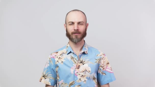 穏やかなひげを生やした男の肖像画カメラを着て 白い背景に隔離された花蓮のシャツを見て 感情の概念 — ストック動画