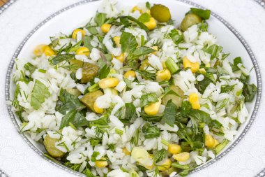 rice with pickled cucumbers, corn seeds and herbs. healthy food. close up.