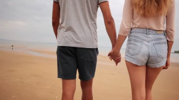 Пара влюбленных, смотрящих друг на друга и гуляющих по морскому пляжу — стоковое видео