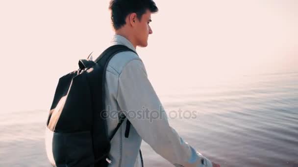Ο νεαρός άντρας παίρνει ένα μήνυμα στο smartphone στην παραλία — Αρχείο Βίντεο