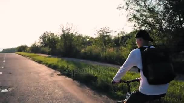 Jovem bonitão a andar na estrada do campo. Desportivo cara de ciclismo na pista . — Vídeo de Stock