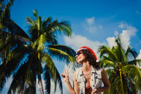 Primer plano de una joven delgada chica sexy en gafas de sol y un sombrero rojo de Santa Claus en Navidad en el Año Nuevo — Foto de Stock