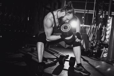 Yakışıklı ve kaslı bir adam, spor salonunda kameraya poz veriyor.