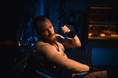 Yakışıklı ve kaslı bir adam, spor salonunda kameraya poz veriyor.