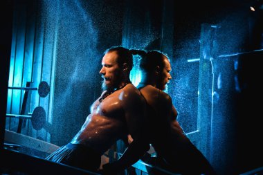 Yakışıklı ve kaslı bir adam, spor salonunda kameraya poz veriyor.