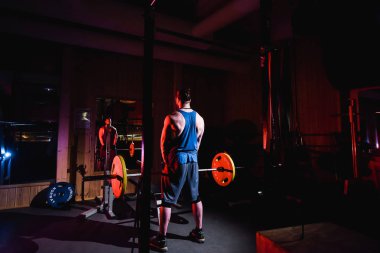 Yakışıklı ve kaslı bir adam, spor salonunda kameraya poz veriyor.