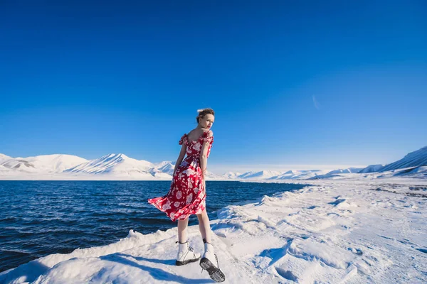 女孩穿着红色山脉斯瓦尔巴群岛在斯匹次卑尔根市朗伊尔城，在阳光明媚的天气背景霜苗条美丽的金发女郎 — 图库照片