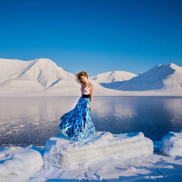 Chica delgada hermoso pelo rojo en un vestido azul en la escarcha sobre un fondo de montañas svalbard en la ciudad de Spitsbergen Longyearbyen — Foto de Stock