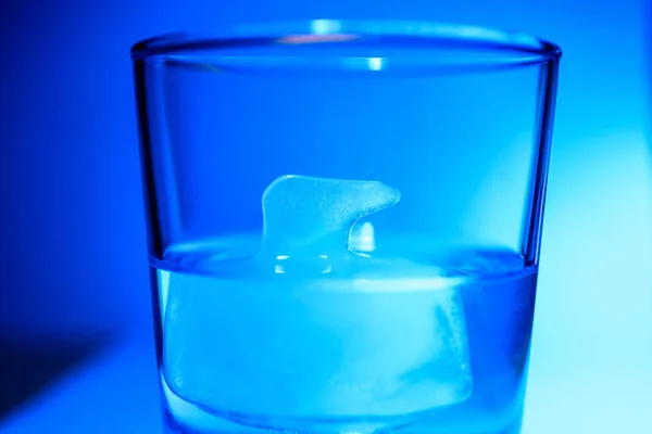 Ein Glas Wasser in Großaufnahme auf einem Blau mit Eis in Form eines Eisbären — Stockfoto