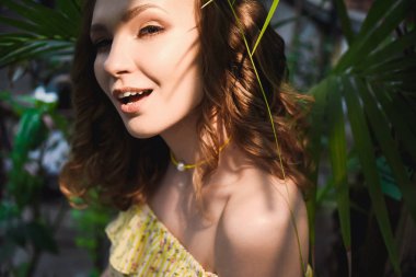 Yakın çekim portre kıvırcık saçları sarı yaz ile genç güzel kız elbise tropikal ormanda