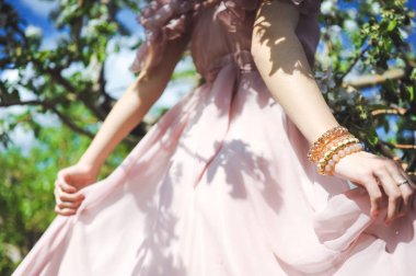 Kız bir gelinlik için sarılmak ve poz başında bir arka plan Bahçe ve mavi gökyüzü ve onlar çiçek çelenk ile uçan pembe elbise 