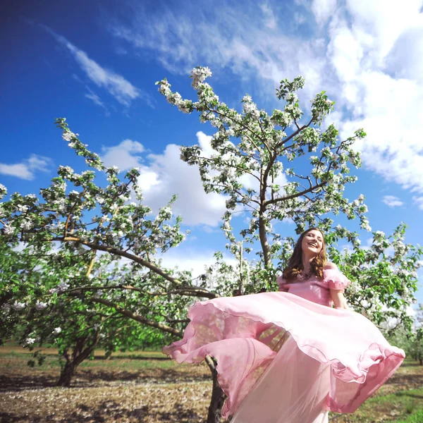 Girl  looking for a wedding dress, a pink dress flying with a wreath of flowers on her head on a background  garden and the blue sky, and they hug and pose — Stock Photo, Image