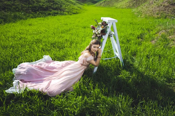 Girl  looking for a wedding dress, a pink dress flying with a wreath of flowers on her head on a background  garden and the blue sky, and they hug and pose — Stock Photo, Image