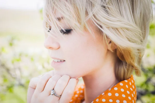 Retrato ao ar livre jovem menina bonita em uma laranja hipster loira brilhante alegre polka ponto blusa, sorrindo lábios gordos vermelhos no fundo da grama verde — Fotografia de Stock