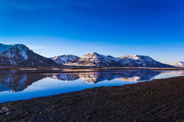 Paisaje del Océano Ártico y la reflexión con el cielo azul y las montañas de invierno con nieve, Noruega, Spitsbergen, Longyearbyen, Svalbard —  Fotos de Stock