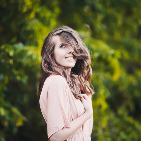 Bela senhora atraente de uma jovem menina morena delgada com vestido longo andando por um parque verde com flores ao pôr do sol estilo de vida — Fotografia de Stock