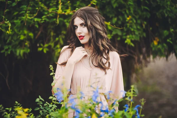 Gyönyörű, vonzó hölgy egy fiatal karcsú barna lány séta egy zöld park sunset életmód virágok hosszú ruha — Stock Fotó