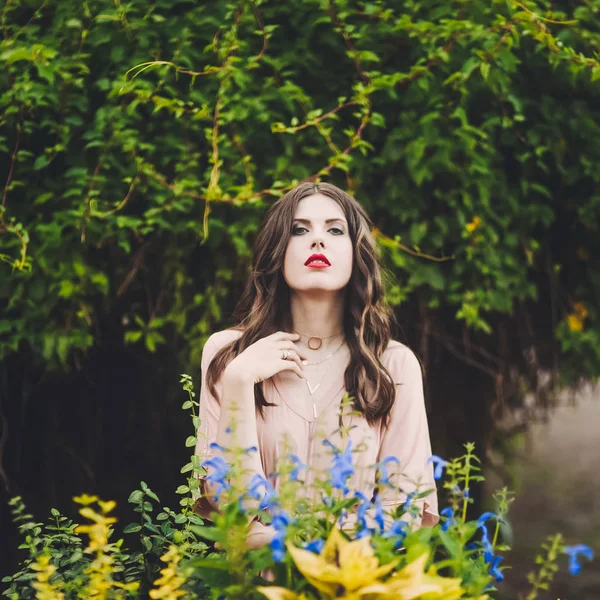 Belle dame attrayante d'une jeune fille brune mince avec robe longue marchant dans un parc verdoyant avec des fleurs au coucher du soleil style de vie — Photo