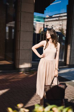 güzel bir ince genç kız blogger portresi şehir merkezinde esmer dusseldorf pastel elbise ve bir Bayan yürüyüş pozlar ve günbatımı üzerinde gülümseyen güneş gözlüğü takıyor