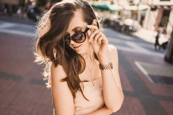 Retrato de uma jovem blogueira esbelta bela morena no centro da cidade dusseldorf em um vestido pastel e uma senhora vestindo óculos escuros andando poses e sorrindo no pôr do sol — Fotografia de Stock