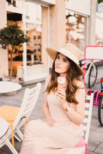 Porträt einer schlanken jungen Bloggerin schöne Brünette in der Düsseldorfer Innenstadt in einem Pastellkleid und einer Sonnenbrille, die in Pose geht und in einem Café mit Eis lächelt — Stockfoto