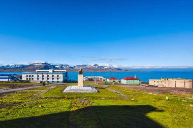 Landscape of the Russian  city of Barentsburg on the Spitsbergen archipelago in the summer in the Arctic In sunny weather and blue sky clipart