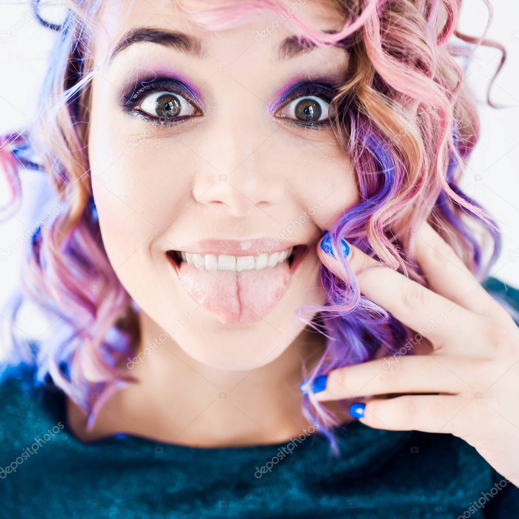 close-up portrait in studio isolated beautiful sexy young blond hipster girl with lilac and pink hair posing with tooth smile