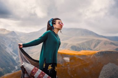 saç dreadlock bulutlu gökyüzü arka plan ve dans Gürcistan sonbahar dağlar bir boho çingene hippi tarzı giysili bir genç güzel hipster kızla güneş gözlüğü portresi