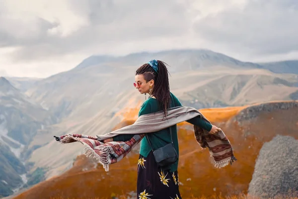 saç dreadlock bulutlu gökyüzü arka plan ve dans Gürcistan sonbahar dağlar bir boho çingene hippi tarzı giysili bir genç güzel hipster kızla güneş gözlüğü portresi
