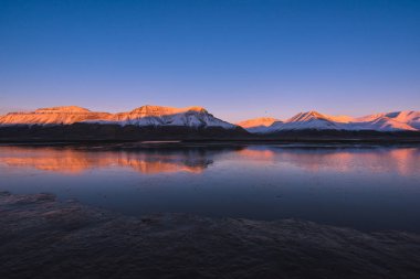Doğada Spitsbergen Svalbard yansıma okyanus Dağları Norveç şehir Longyearbyen yakınında bir pembe günbatımı manzara