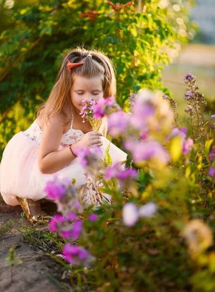 Niña hermosa sonriente bailando en vestido rosa tutú como bailarina en día soleado feliz infancia sobre un fondo de florecimiento verano en flores —  Fotos de Stock