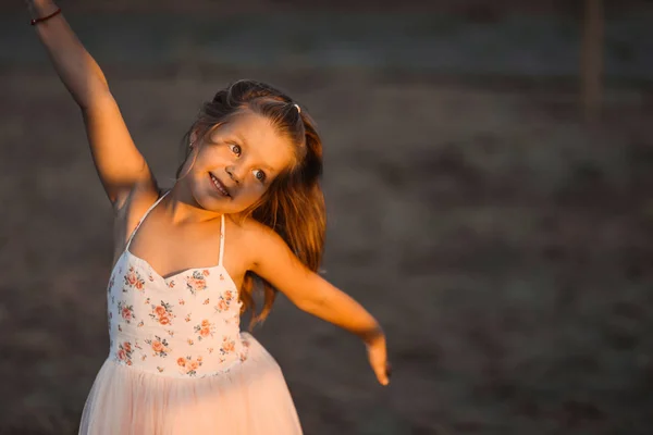 Маленька дівчинка красива усміхнена танцює в рожевій сукні, як балерина в сонячний день щасливе дитинство — стокове фото