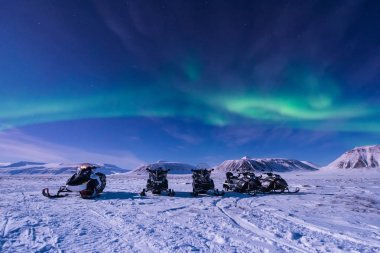 The polar arctic Northern lights aurora borealis sky star in Norway Svalbard in Longyearbyen city snowmobile the moon mountains