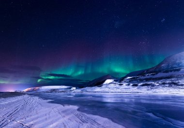 The polar arctic Northern lights aurora borealis sky star in Norway Svalbard in Longyearbyen city town mountains clipart