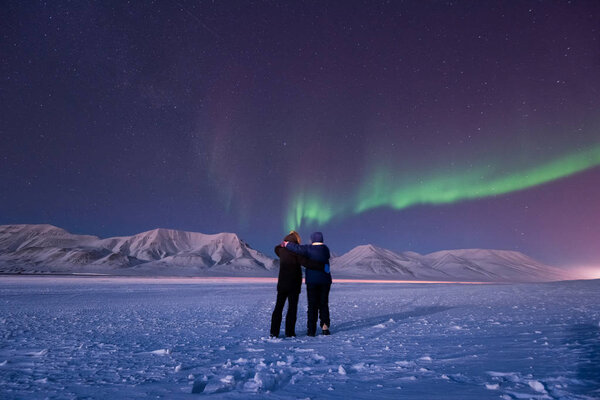 The polar arctic Northern lights aurora borealis sky star in Norway Svalbard in Longyearbyen city man people mountains