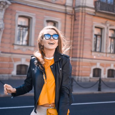 Genç ve seksi bir kızın portresi hippi güneş gözlüklü güzel sarışın gülüyor ve St. Petersburg şehrinin arka planında poz veriyor.