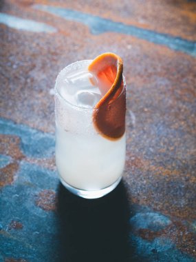 Beyaz roily kokteyl pürüzsüz bir şeffaf cam buz küpleri ile taze greyfurt paslı bir arka plan üzerinde sağ parçası ile dekore edilmiştir. Arka ışık, dikey yönlendirmesi, Merkezi kompozisyon