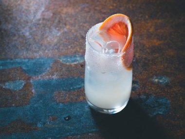 Beyaz roily kokteyl pürüzsüz bir şeffaf cam buz küpleri ile taze greyfurt paslı bir arka plan üzerinde sağ parçası ile dekore edilmiştir. Arka ışık, dikey yönlendirmesi, metin alanı