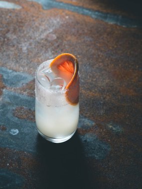 Beyaz roily kokteyl pürüzsüz bir şeffaf cam buz küpleri ile taze greyfurt paslı bir arka plan üzerinde sağ parçası ile dekore edilmiştir. Arka ışık, dikey yönlendirmesi, metin alanı