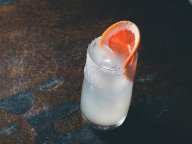 Beyaz roily kokteyl pürüzsüz bir şeffaf cam buz küpleri ile taze greyfurt paslı bir arka plan üzerinde sağ parçası ile dekore edilmiştir. Moody ışık, yatay yönlendirme, metin alanı