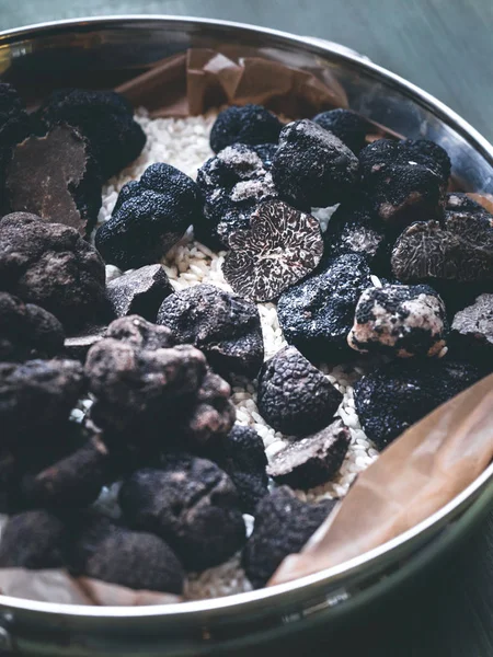 Molti funghi al tartufo nero in una pentola metallica, alcuni tagliati a metà, altri interi. Un tartufo da vicino con una bella consistenza. sfondo in legno turchese, orientamento verticale — Foto Stock