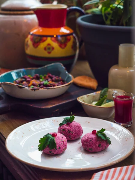 Salade de betteraves géorgiennes Pkhali avec noix et herbes sur une assiette blanche, pot coloré et boisson aux fruits et haricots sur un fond. Photo verticale — Photo